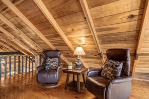 Curl up in these cozy leather recliners beneath soaring wood beams, where rustic warmth meets modern comfort in your private loft retreat.