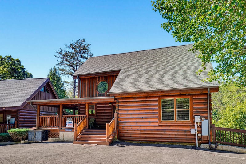 Charming log cabin exterior surrounded by mature trees, offering a secluded mountain retreat with convenient parking just steps from your front door.