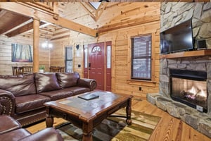Cozy up by the crackling stone fireplace in this rustic living room, where rich leather seating and warm wood create your perfect mountain retreat.