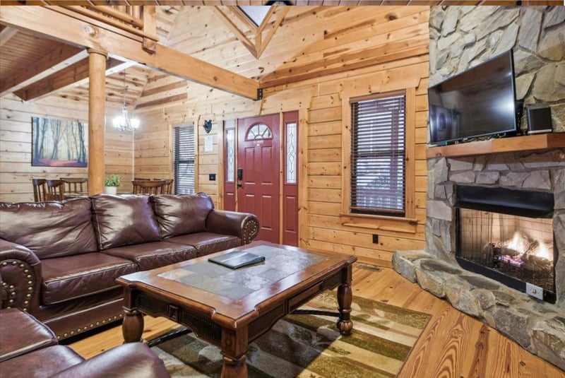 Cozy up by the crackling stone fireplace in this rustic living room, where rich leather seating and warm wood create your perfect mountain retreat.