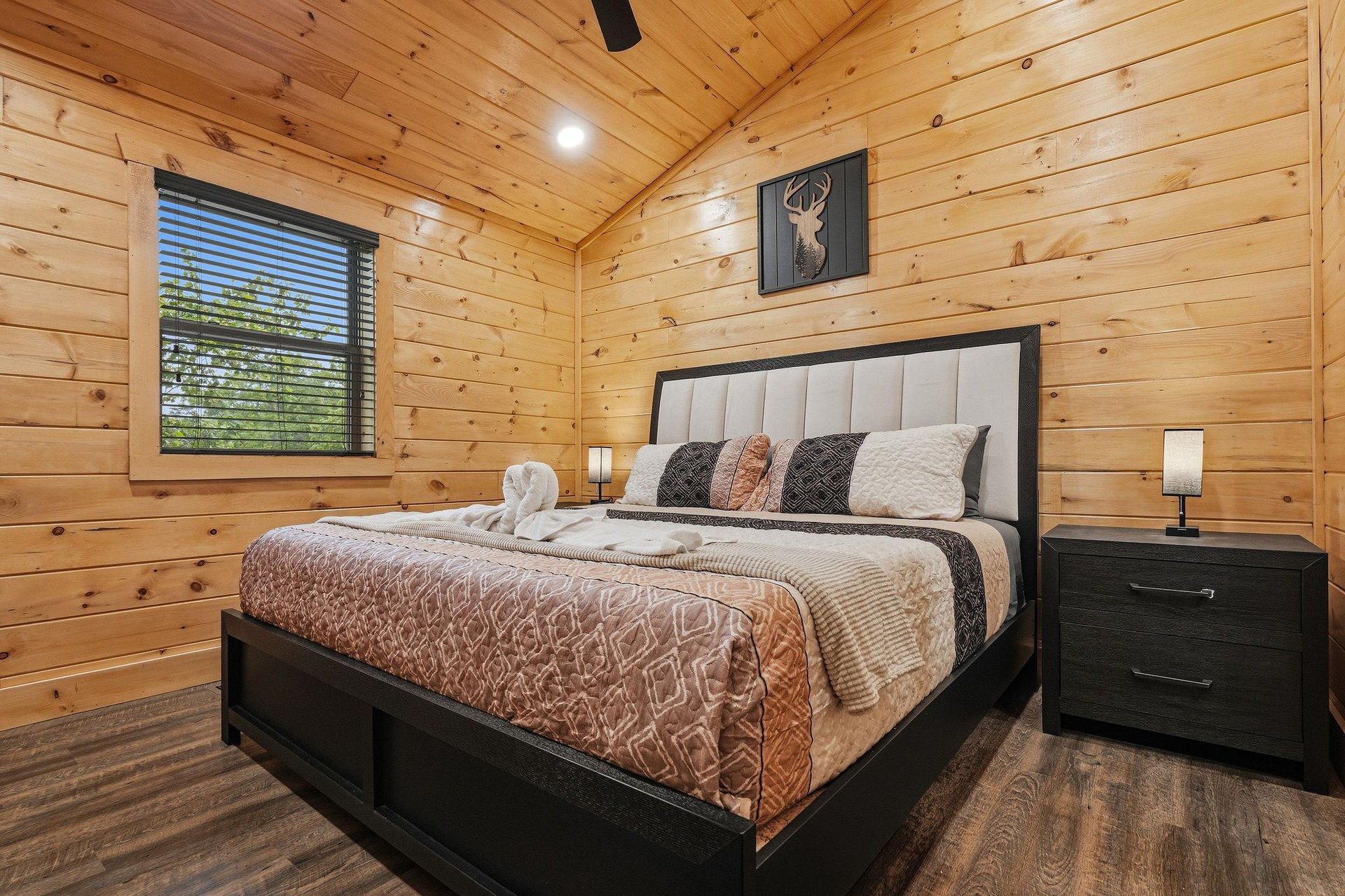 Retreat to your cozy cabin bedroom where warm wood walls embrace plush bedding and forest views invite peaceful slumber.