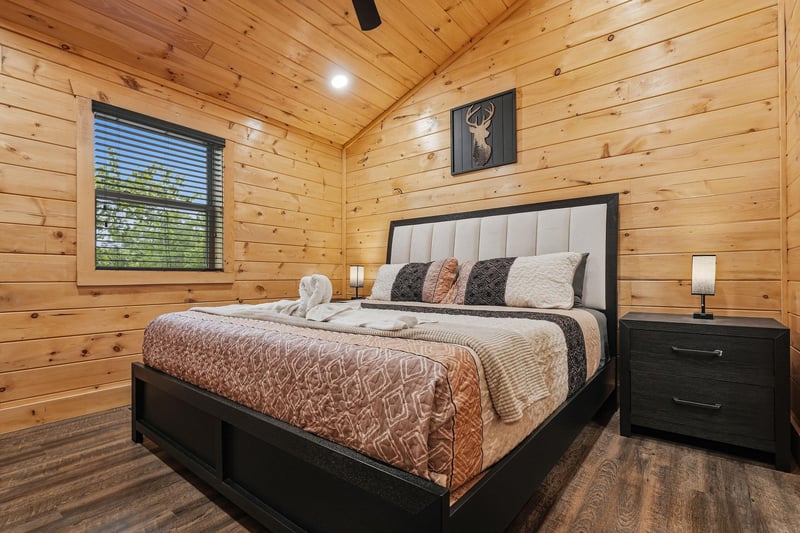 Retreat to your cozy cabin bedroom where warm wood walls embrace plush bedding and forest views invite peaceful slumber.