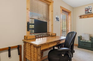 Your rustic workspace features a handcrafted wooden desk beneath windows framed in natural pine, letting in warm daylight as you settle in to stay connected.