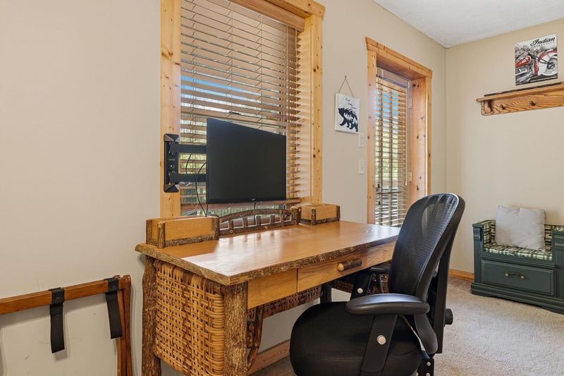 Your rustic workspace features a handcrafted wooden desk beneath windows framed in natural pine, letting in warm daylight as you settle in to stay connected.
