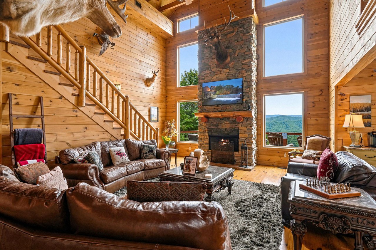 Relax in your spacious mountain cabin with soaring ceilings, a cozy stone fireplace, and stunning views of rolling peaks. Sink into plush leather seating and soak in the rustic elegance.