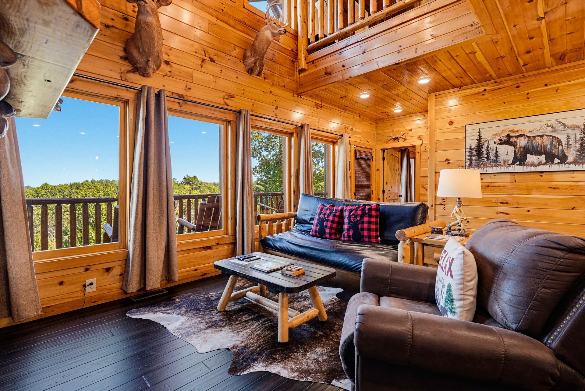 Settle into this cozy cabin living space, where rustic charm meets modern comfort. Floortoceiling windows frame stunning forest views, while hunting lodge décor and plush seating invite you to unwin