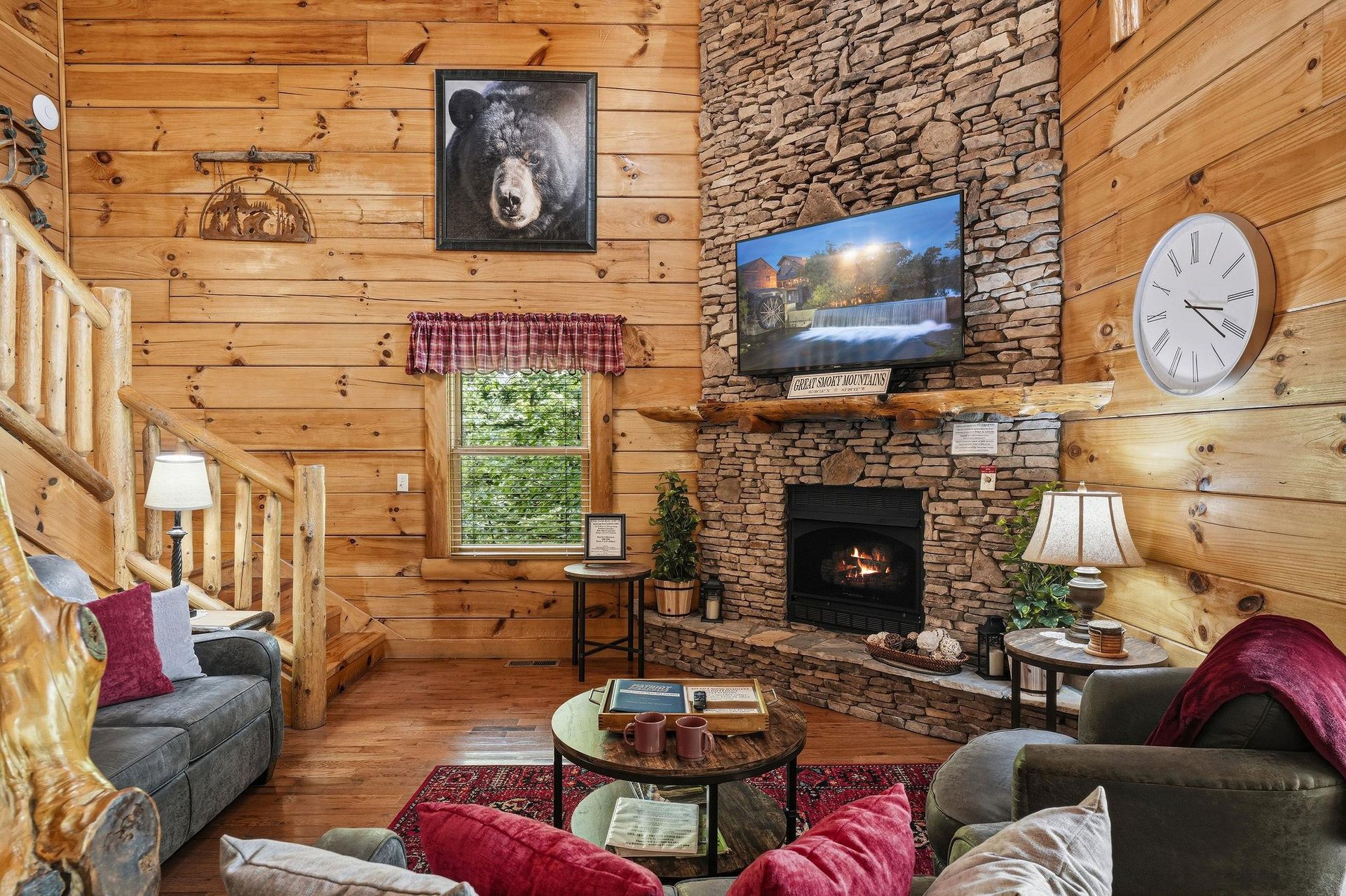 Cozy up in your inviting living room where rustic wood walls meet a stunning stone fireplace—perfect for unwinding after mountain adventures.