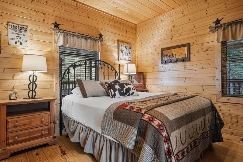 Sink into comfort in this charming cabin bedroom, where warm wood surrounds you and westerninspired touches create a cozy retreat after a day of adventure.