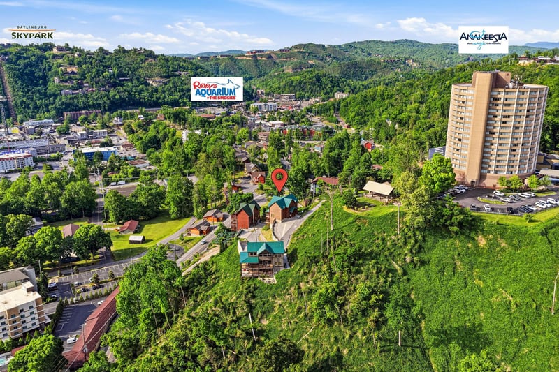 Aerial perspective of the property location within Gatlinburgs lush surroundings, marked by a pin and nestled among forested hills and nearby attractions.