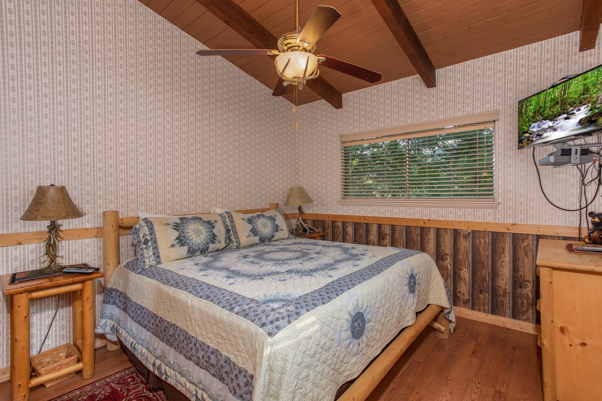 Kingsized log bed in a bedroom with a TV and dresser at Bushwood Lodge, a 3bedroom cabin rental located in Gatlinburg