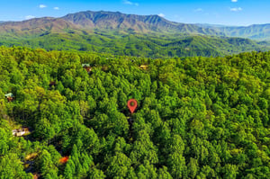 Aerial view showcases the propertys secluded location nestled among dense forests with stunning mountain ranges creating a dramatic backdrop.