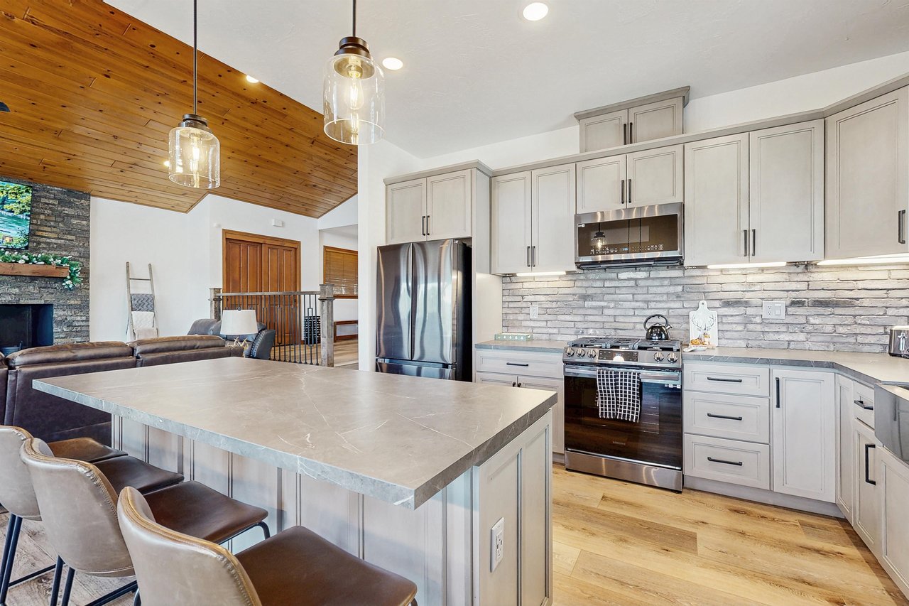 Stainless steel appliances, cooking essentials, kitchen island, and counter seating for 4 guests.