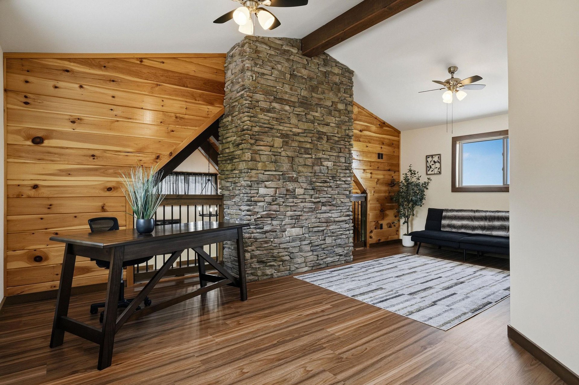 Warm wood paneling and a striking stone accent wall anchor your cozy retreat, blending rustic charm with modern comfort for a space that feels both inviting and serene.