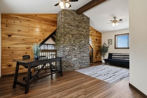 Warm wood paneling and a striking stone accent wall anchor your cozy retreat, blending rustic charm with modern comfort for a space that feels both inviting and serene.