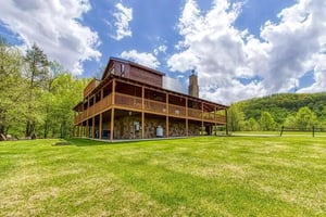 A rustic cabinstyle property set on expansive private grounds, surrounded by rolling hills and lush woodlands—an ideal countryside escape.