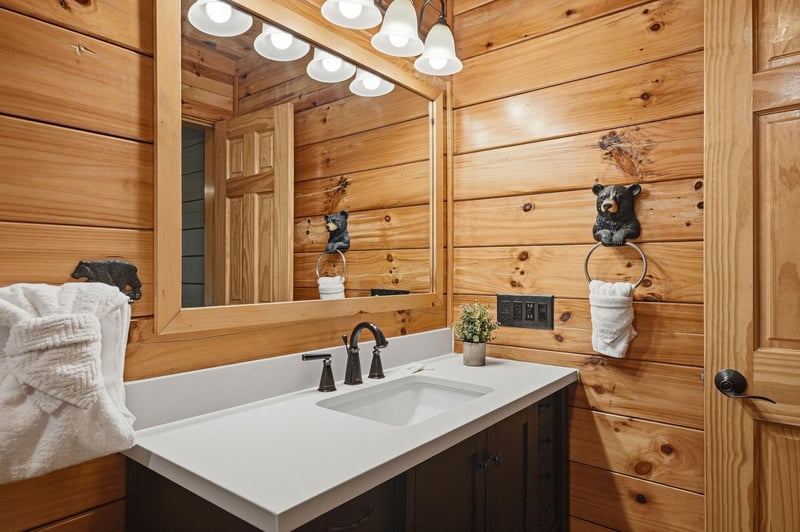 Warm up in this cozy cabin bathroom, where rich pine walls and playful bearthemed accents create a charming mountain retreat. Fresh towels await you after a refreshing soak.