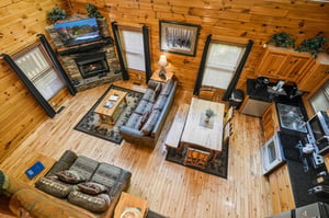 A sweeping view reveals your expansive, openconcept living space with soaring vaulted ceilings, rustic wood finishes, cozy fireplace, and a wellequipped kitchen. Sunlight streams through tall window