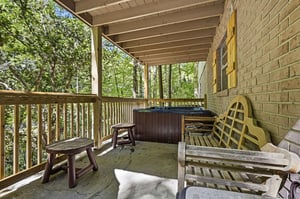Unwind on your private covered balcony with a hot tub surrounded by peaceful wooded views. Natural light filters through the trees as you relax in your own secluded retreat.