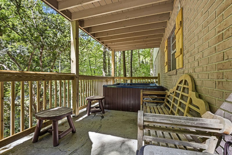 Unwind on your private covered balcony with a hot tub surrounded by peaceful wooded views. Natural light filters through the trees as you relax in your own secluded retreat.