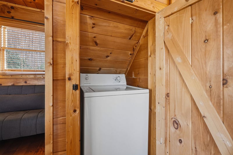 Your cozy cabin features convenient inunit laundry tucked beneath rustic wood stairs, making extended stays effortless.