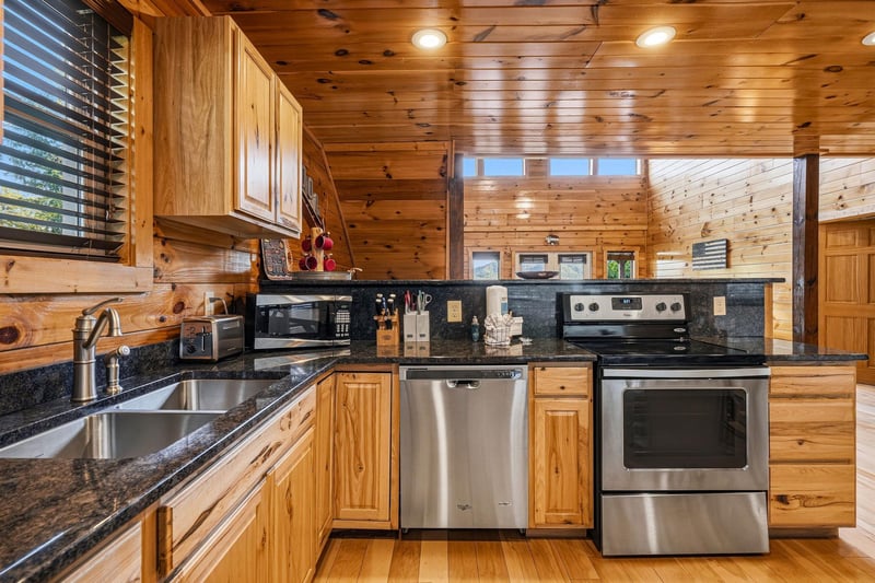 Your fully equipped kitchen features granite counters, stainless steel appliances, and warm wood cabinetry—perfect for preparing homecooked meals during your mountain getaway.