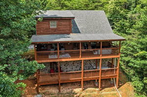A charming multilevel cabin with wraparound decks nestled among lush forest, offering peaceful seclusion and rustic mountain charm in a serene natural setting.
