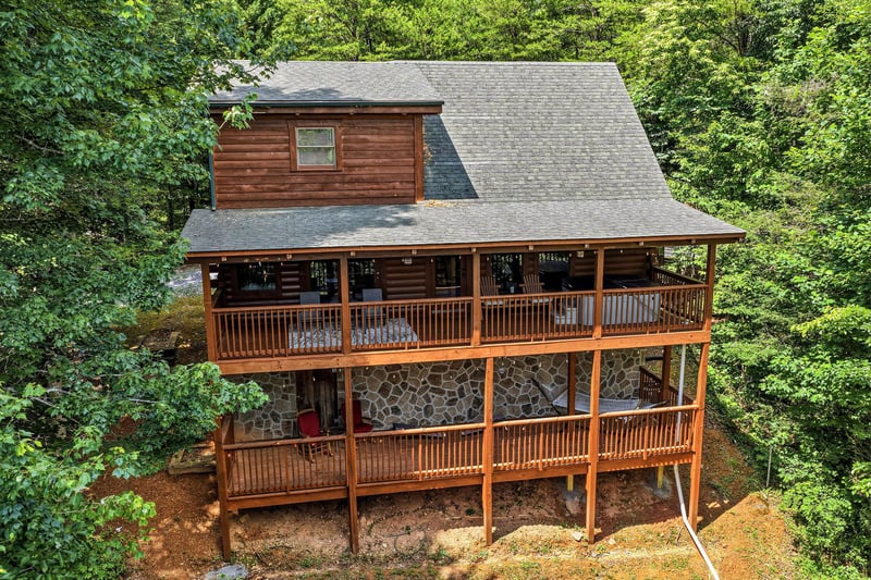 A charming multilevel cabin with wraparound decks nestled among lush forest, offering peaceful seclusion and rustic mountain charm in a serene natural setting.