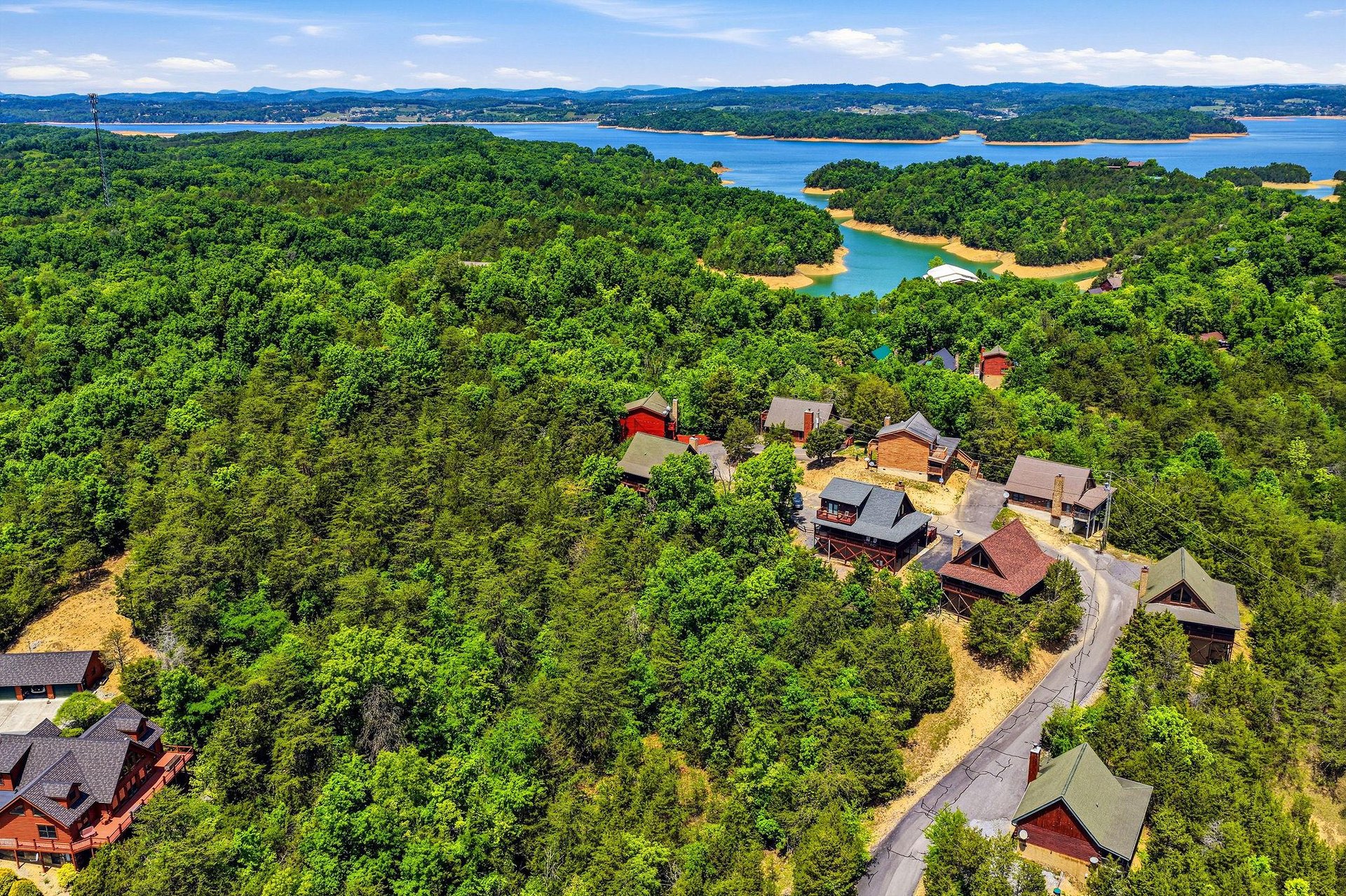 Nestled on a wooded hillside overlooking a serene lake, this peaceful property offers stunning natural surroundings with mountains framing the horizon—an ideal lakeside retreat.