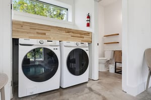 Keep your wardrobe fresh with this sleek laundry setup featuring modern appliances beneath natural wood accents and bright natural light.