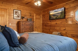 Cozy wooden bedroom with warm lighting and mountain views on TV awaits your peaceful retreat.