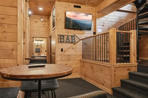 Unwind in your private cabin bar area, where rustic charm meets modern comfort with a cozy round table, mountain views on screen, and easy access to your full bathroom.