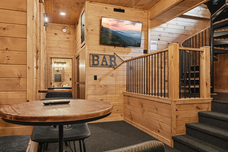 Unwind in your private cabin bar area, where rustic charm meets modern comfort with a cozy round table, mountain views on screen, and easy access to your full bathroom.