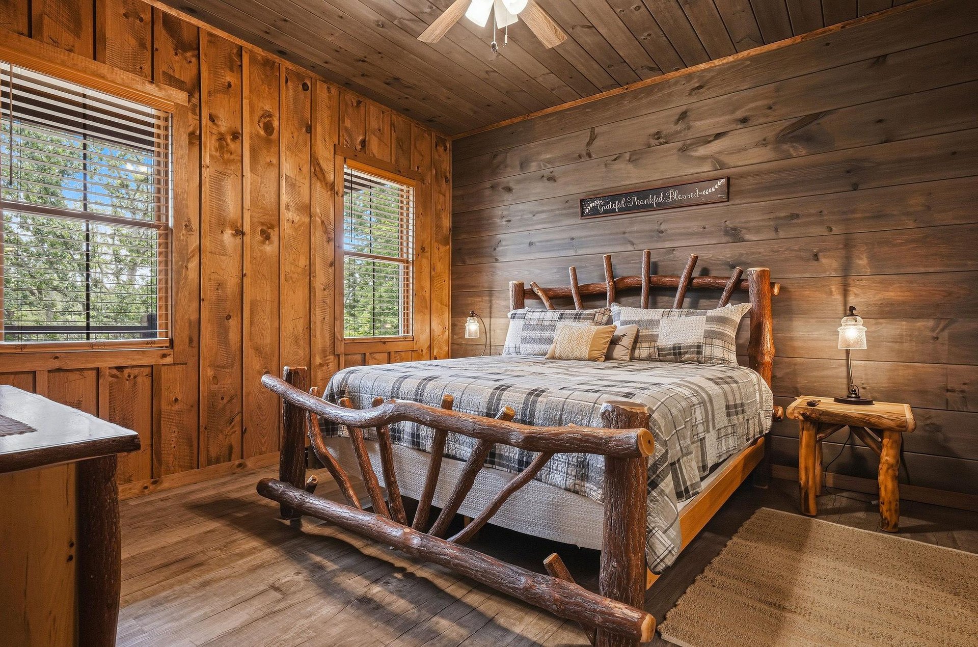 Drift off to sleep in this cozy rustic bedroom, where warm wood tones and a handcrafted log bed create your perfect mountain retreat. Natural light streams through windows framing forest views.