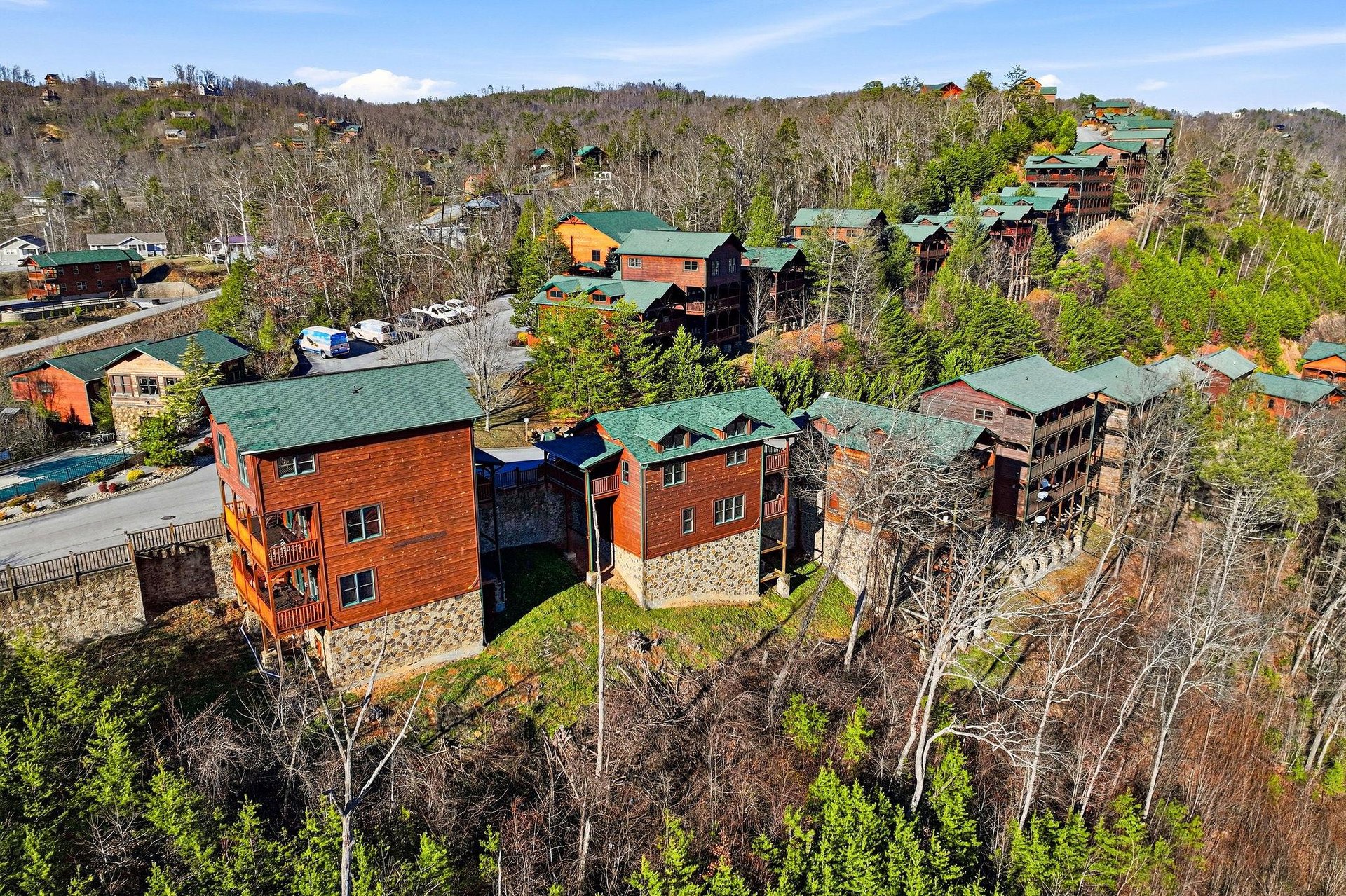 Aerial view of mountain cabins nestled among rolling hills and forest, showcasing the scenic resort community.