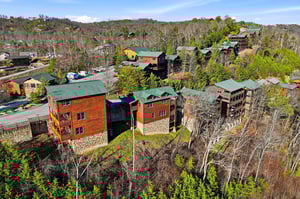 Aerial view of mountain cabins nestled among rolling hills and forest, showcasing the scenic resort community.