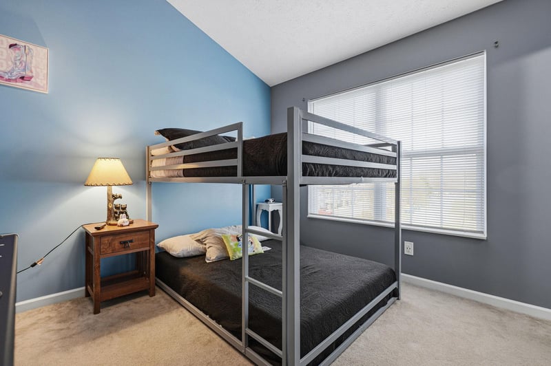 Your kids will love this cozy bunk room with comfortable bedding, warm lamp lighting, and cheerful blue accents creating the perfect sleepover atmosphere.