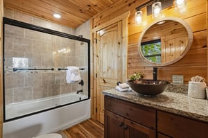 Step into your private retreat featuring a deep soaking tub, elegant vessel sink, and warm wood finishes that create a peaceful, spalike escape after your mountain adventures.