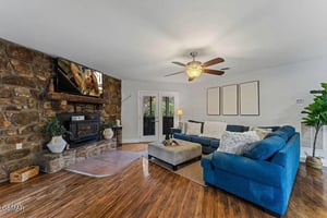 Cozy up in this inviting living room featuring a striking stone fireplace, plush blue sectional, and warm wood floors for perfect relaxation.