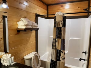 Your private bathroom features rustic wood paneling and fresh white towels, creating a cozy cabin retreat after a day of adventure.