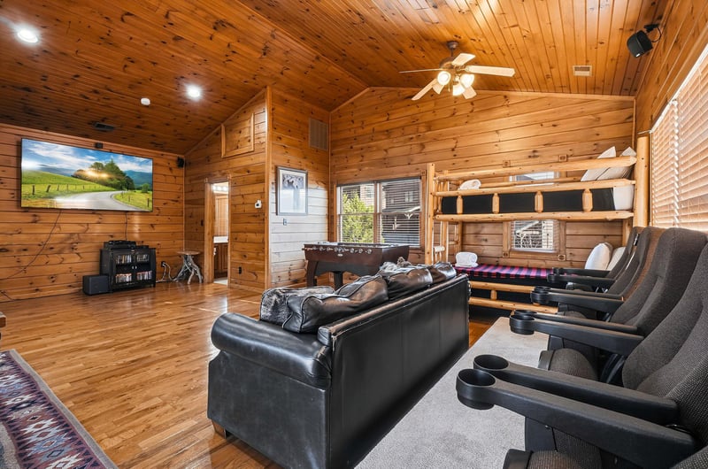 Sink into cozy leather seating and enjoy movie nights on the big screen in your cabins open living space with rustic wood walls, vaulted ceilings, and entertainment ready.