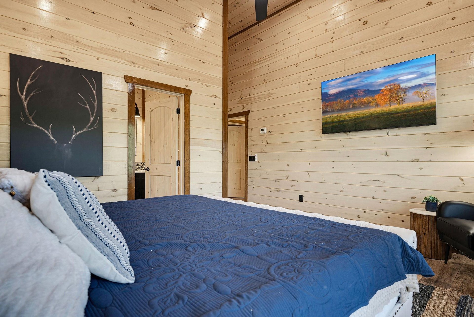 Sink into soft bedding in this serene woodpaneled bedroom, where natural pine surrounds you in warmth. The vaulted ceiling and cozy textures invite peaceful rest.