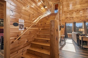 Step into rustic charm with warm wood walls surrounding you, natural light streaming through windows, and a cozy living space perfect for unwinding.