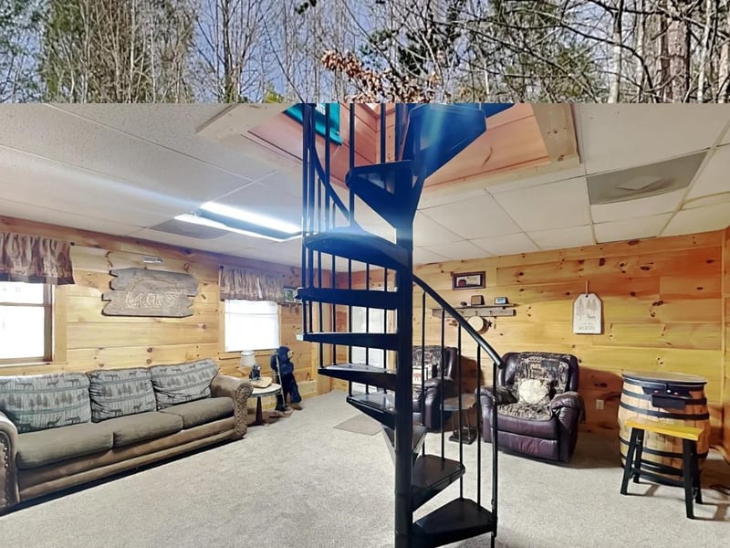 Unwind in your cozy living room with rustic wood walls and a unique spiral staircase leading to your private loft retreat.
