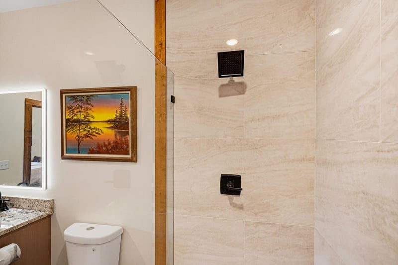 A clean, modern bathroom awaits your refreshing retreat, with a spacious walkin shower finished in elegant neutral tile and a wellappointed vanity just steps away.
