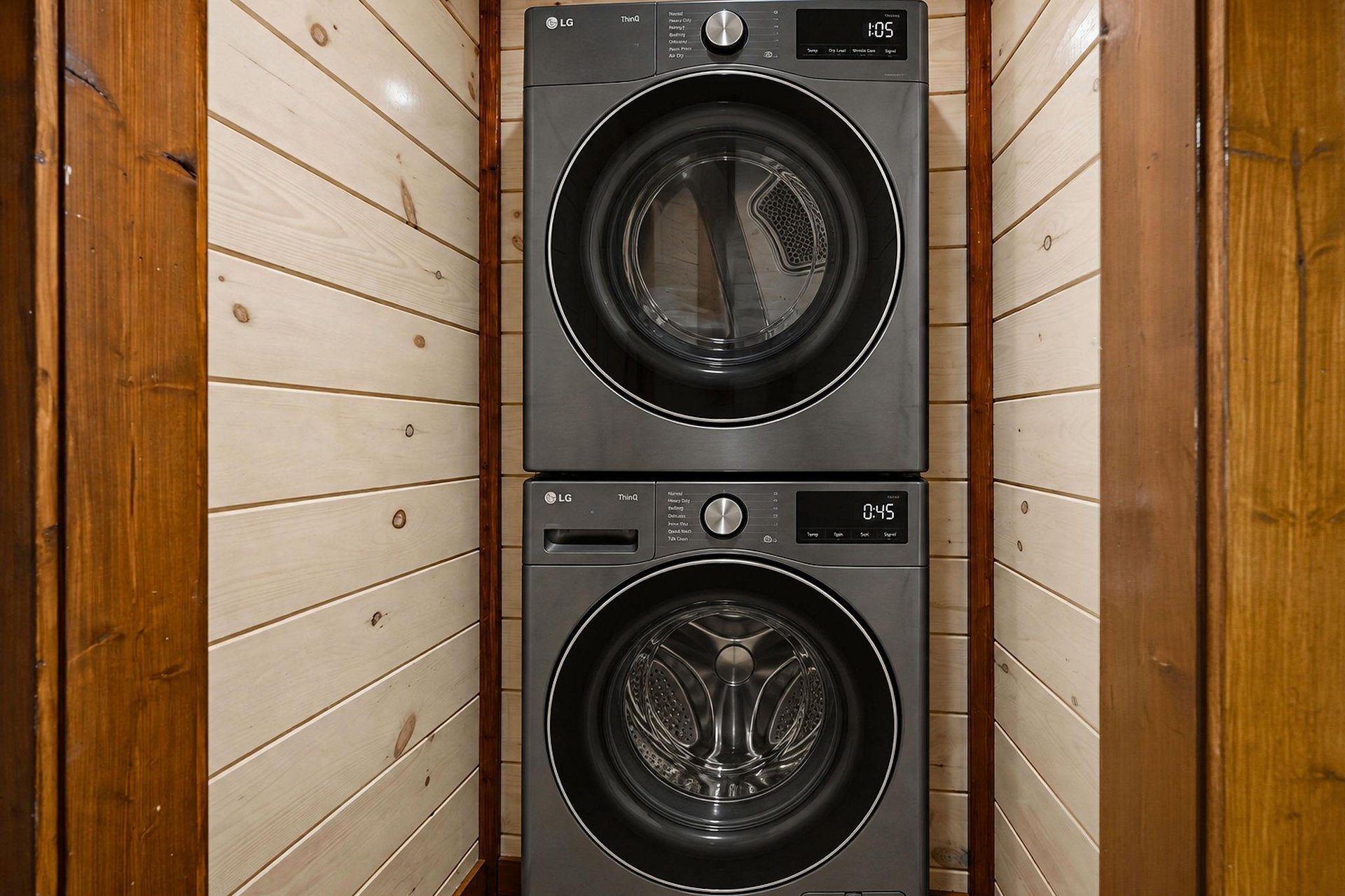 Modern LG stackable washer and dryer set tucked into a cozy woodpaneled closet—your laundry taken care of so you can focus on relaxing.