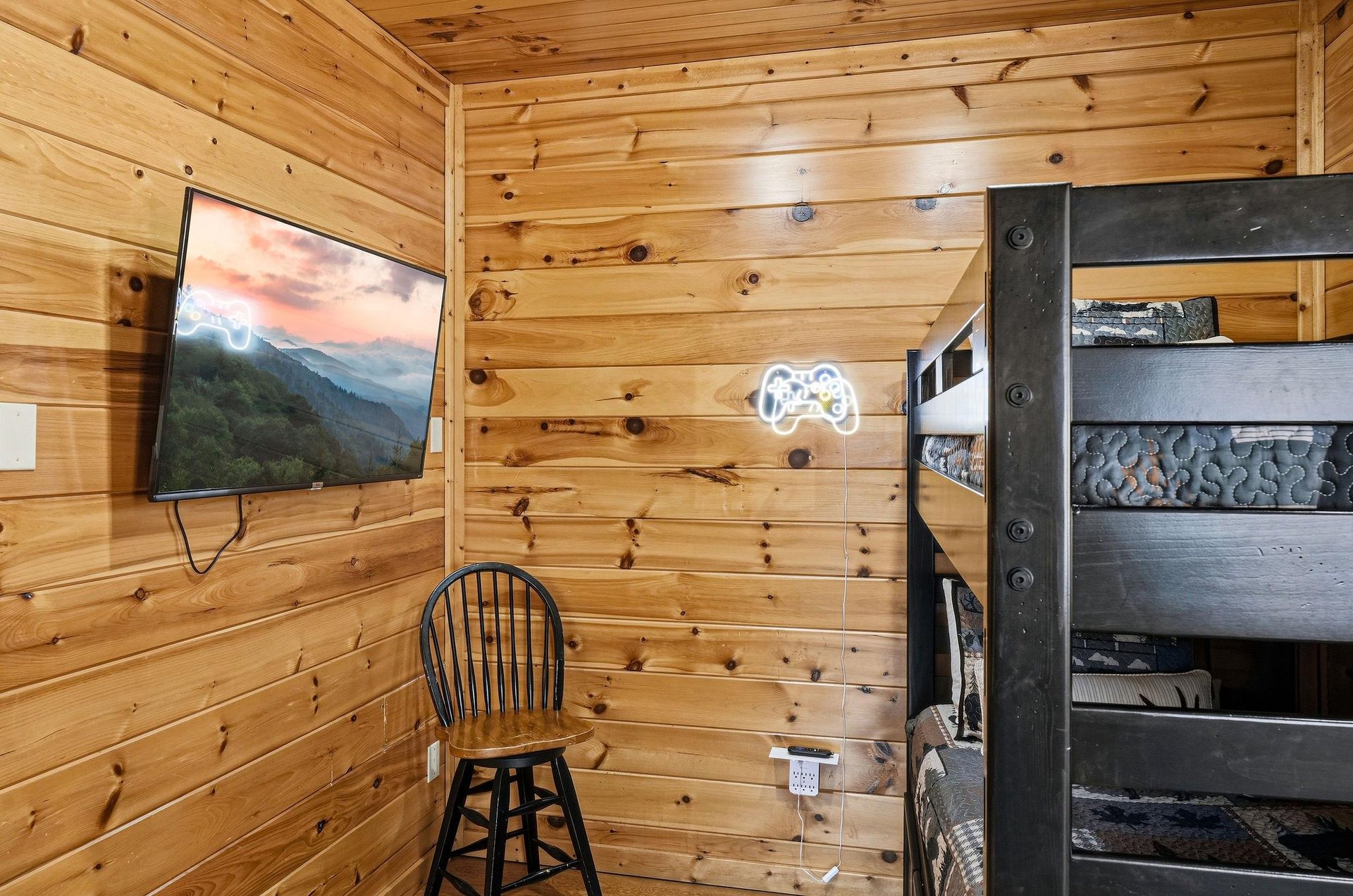 Your cozy cabin bedroom features rustic wood walls, a flatscreen TV, and comfortable bunk beds perfect for relaxing after mountain adventures.