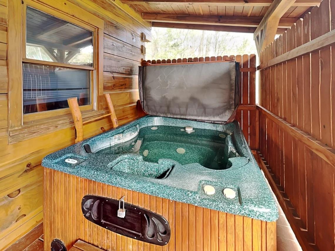 Your private hot tub awaits on the covered deck, surrounded by natural wood and peaceful forest views—perfect for unwinding after a day of adventure.