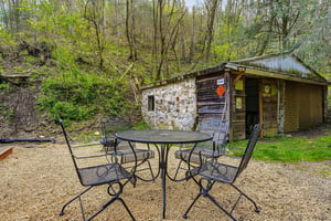 Rustic stone and wood cabin nestled in peaceful woodland setting with outdoor dining area for forest retreats.