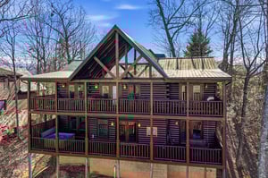 Charming log cabin nestled in wooded surroundings with spacious wraparound decks and rustic mountain architecture.