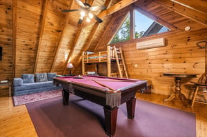 Your rustic game room awaits with a pool table, cozy seating, and charming wooden beams overhead for memorable evenings.